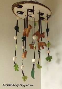 a wooden wind chime hanging from the ceiling with leaves and animals on it's sides