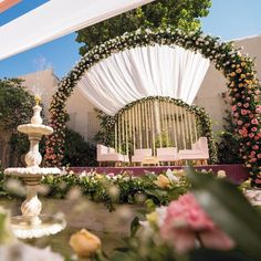 an outdoor wedding setup with flowers and white draping on the back drop cloth