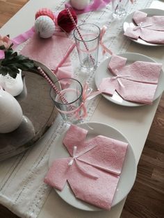 the table is set with pink napkins and place settings