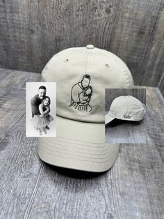 a baseball cap with an image of a man holding a baby in his arms on top of a wooden table