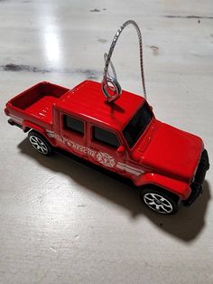 a red toy truck is hanging from a chain