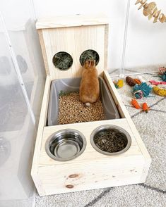 a cat sitting in a wooden box with two bowls on the bottom and one inside