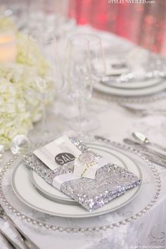 the table is set with silver and white place settings