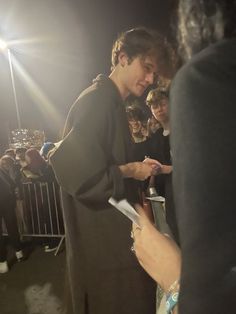 a young man signing autographs for fans at an event in front of a crowd