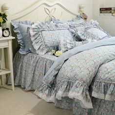 a bed with blue and white ruffled bedspread, pillows and pillow cases