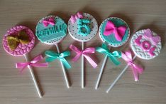 six decorated lollipops with bows and ribbons on them sitting on a table