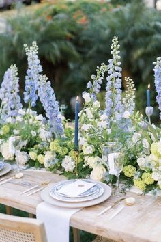 the table is set with blue and white flowers, candles, and place settings for dinner