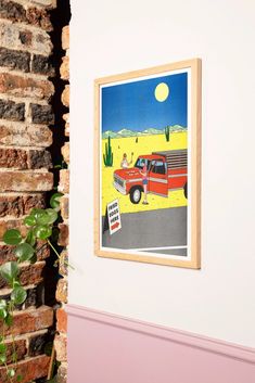 a red truck driving down a street next to a brick wall with a sign on it