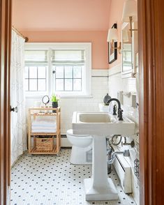 a bathroom with pink walls and white tile on the floor is pictured in this image