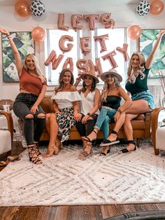 four women sitting on a couch in front of a sign that says let's get party