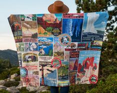 a person holding up a large blanket covered in travel stickers and magnets on the side of a mountain