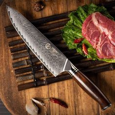 a knife sitting on top of a wooden cutting board next to some vegetables and meat