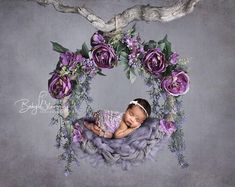 a baby is laying in a nest with purple flowers