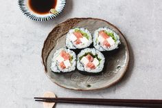 sushi on a plate with chopsticks next to it and a cup of tea