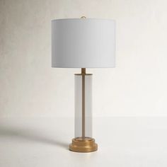 a table lamp with a white shade on it and a gold frame around the base