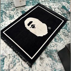 a black and white rug with a gorilla face on the bottom, next to a bottle of deodorant