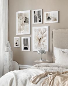 a bed with white sheets and pictures hanging on the wall above it in a bedroom