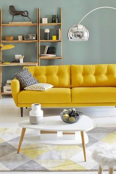 a living room with yellow couches and white coffee table in front of a bookshelf