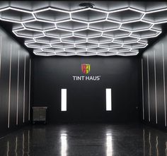 an empty room with the tint haus logo lit up on it's ceiling