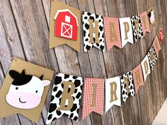 a cow themed birthday banner hanging on a wooden fence with farm animals and barnyard decorations