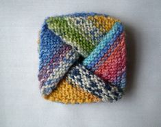 a multicolored knitted headband laying on top of a white surface