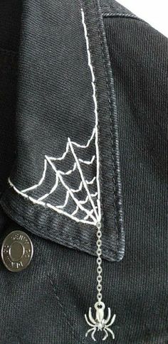 a spider web on the back of a black jacket with a coin attached to it