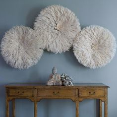 three white balls hanging on the wall above a wooden table with two small vases