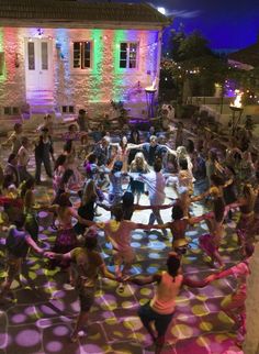 a large group of people doing various activities in front of a building with colored lights