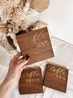 two wooden coasters with the words table three and one that has gold lettering on them