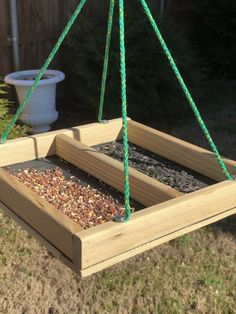 a bird feeder hanging from a tree in the yard with some birdseed inside it