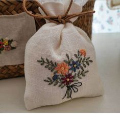 a small bag with flowers on it sitting next to a basket filled with other items