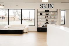 the interior of a skin store with large windows and white couches in front of them