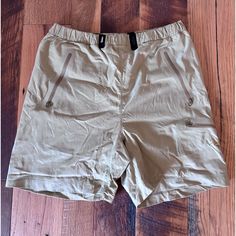 a pair of tan shorts sitting on top of a wooden floor