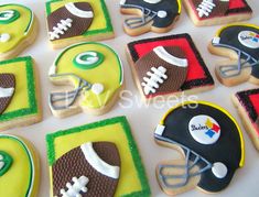 decorated cookies are arranged in the shape of footballs and helmets on a white table