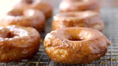 glazed donuts cooling on a wire rack with the words new in blue above them