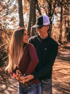 a young man and woman are standing together in the woods looking into each other's eyes