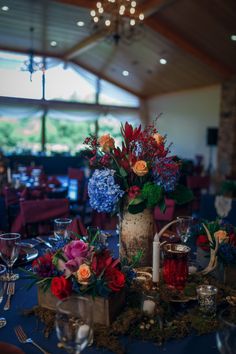 a vase filled with flowers sitting on top of a blue table cloth covered dining room