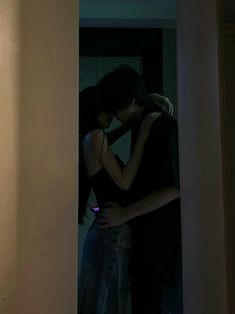 a man and woman standing next to each other in front of a door with their arms around each other