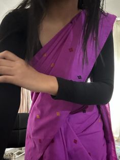 a woman wearing a purple sari and black leggings is holding her arm