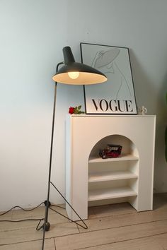 the lamp is on next to an empty book shelf and a white cabinet with a plant in it