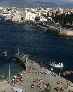 people are sitting on the beach next to the water