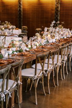 a long table is set up with white linens and wooden chairs for an elegant dinner