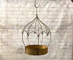 a metal bird feeder hanging from a brick wall