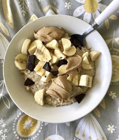 a bowl filled with oatmeal topped with bananas and chocolate chips next to a spoon