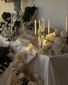 a table topped with lots of white flowers and candles