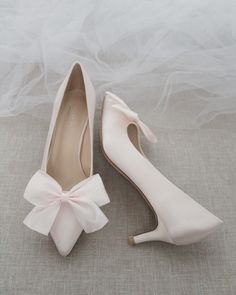 a pair of shoes with a pink bow on the heel and veil in the background