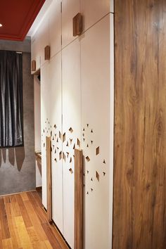 an empty room with wooden floors and white cupboards on the wall next to a window