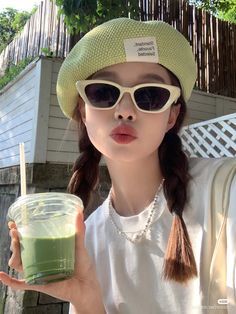 a woman wearing sunglasses and a hat holding a drink