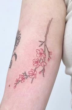 a woman's arm with red flowers and leaves on the left side of her arm