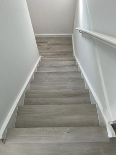 an empty staircase with white walls and wood flooring on the bottom, leading up to the second floor